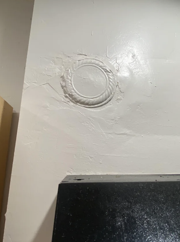 Wall with circular patch above a black countertop, indicating repair