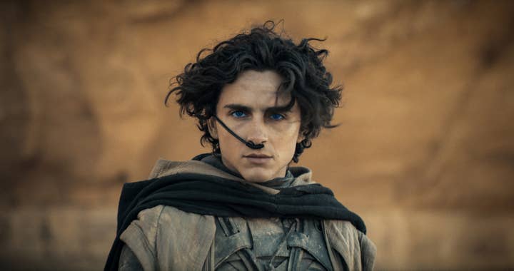 Person in character as Paul Atreides with a futuristic desert outfit and intense gaze