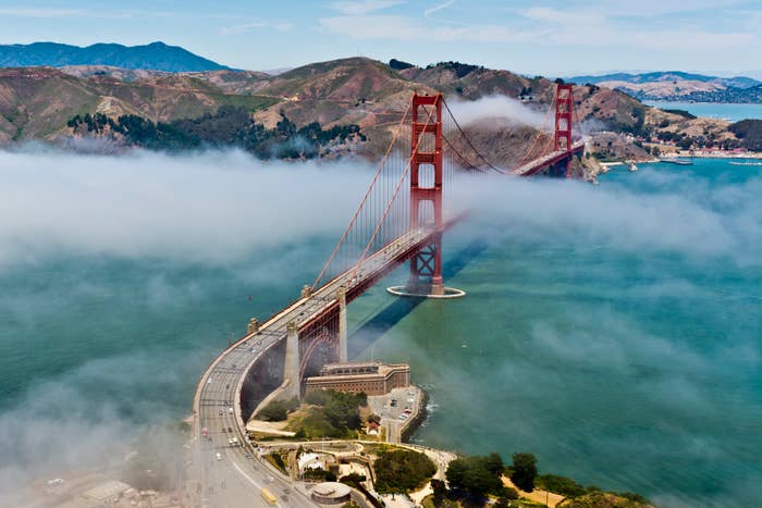 Golden Gate Bridge partially obscured by fog, with traffic and surrounding landscape