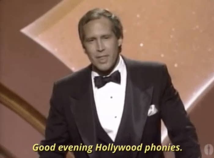 chhevy chase in tuxedo on stage with text overlay "Good evening Hollywood phonies."