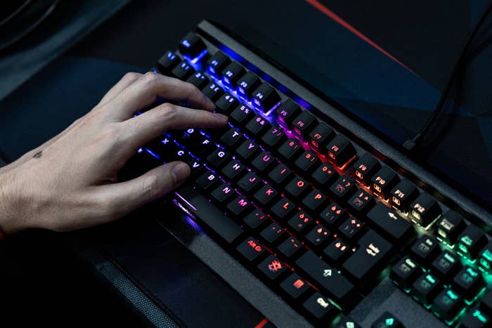 Close-up of a hand typing on a backlit mechanical keyboard