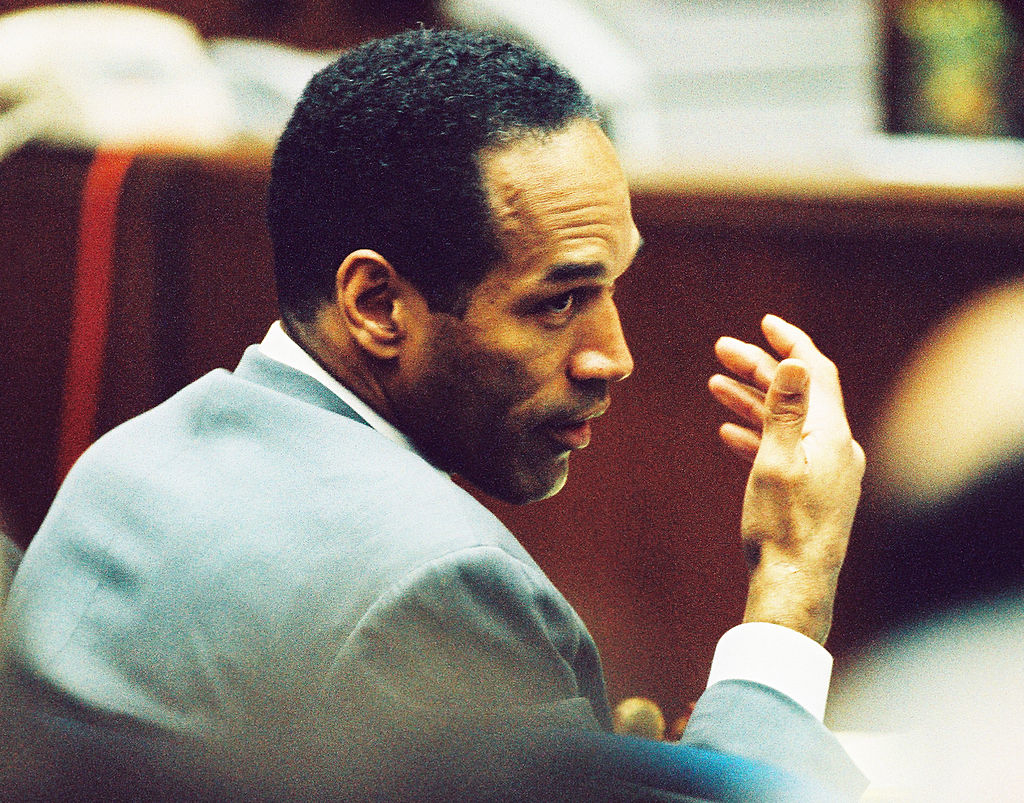 O.J. Simpson seated in court wearing a suit, looking pensive
