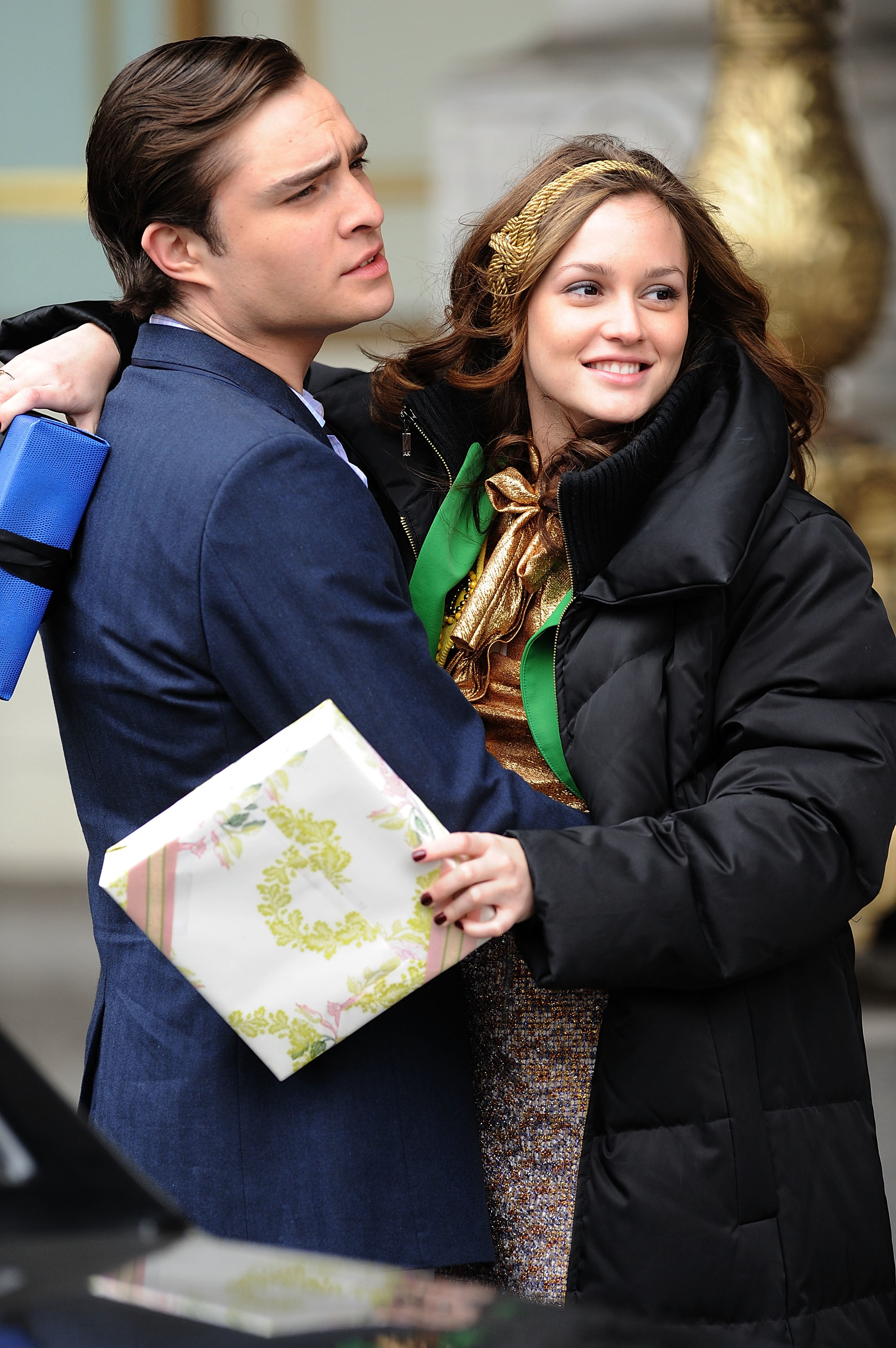 Chuck Bass and Blair Waldorf from Gossip Girl in an outdoor scene, embracing and holding a gift