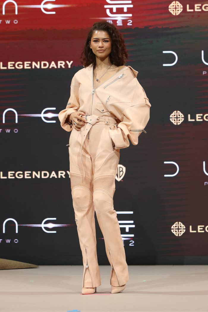 Zendaya in a peach jumpsuit with zipper details stands on stage