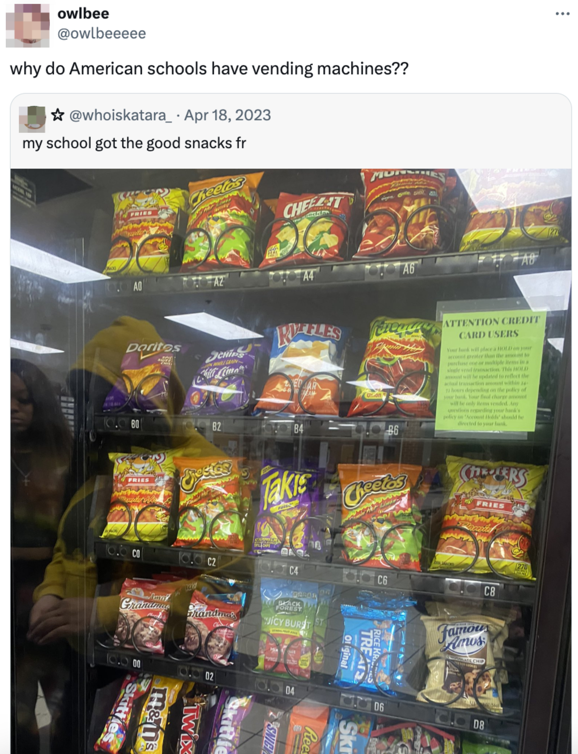Vending machine filled with various snacks like chips and candies, with a reflection of a person on the glass