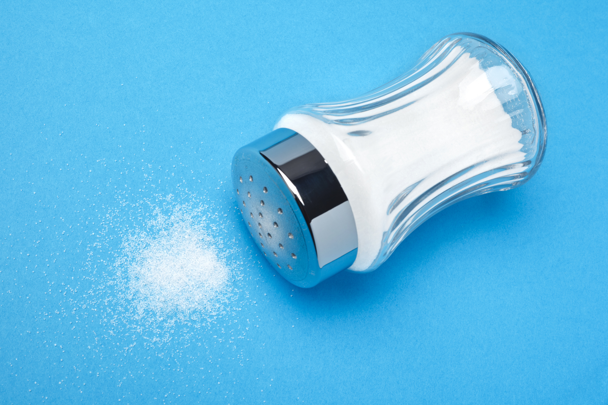 A spilled salt shaker on a blue background