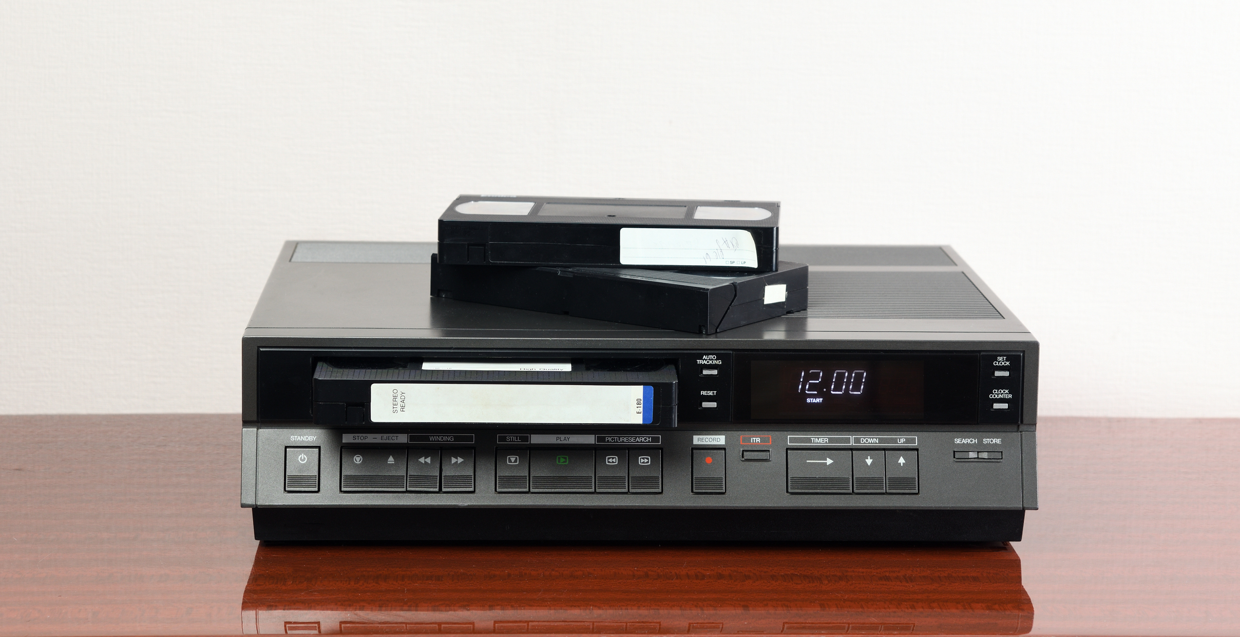 A VCR with VHS tapes on top