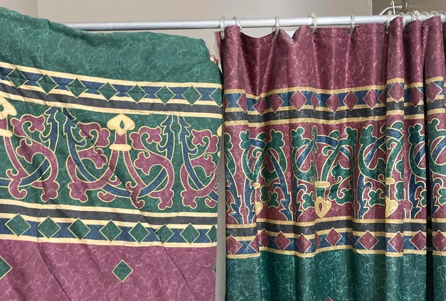 Two shower curtains with mismatched patterns hang side by side