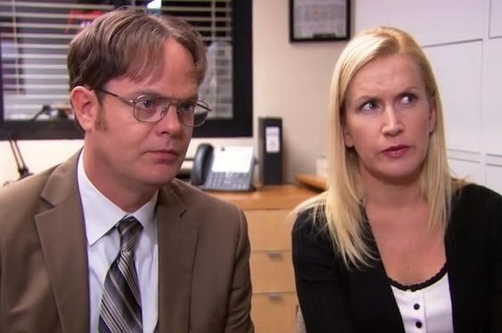 Dwight Schrute and Angela Martin from The Office sitting in an office, looking skeptically to their right
