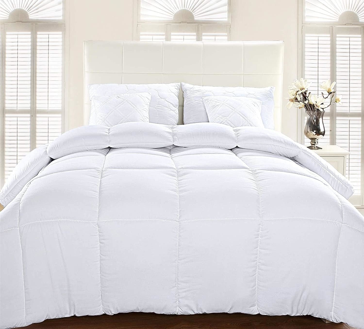 A plush white comforter set displayed on a neat bed with matching pillows in a bright bedroom setting