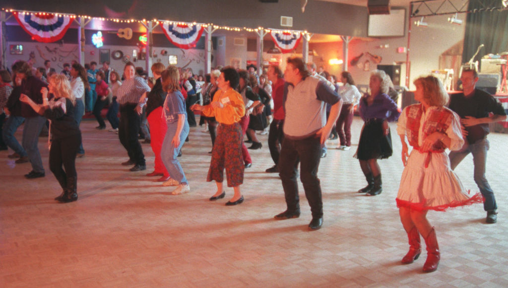 People in casual attire dancing in a hall decorated with bunting