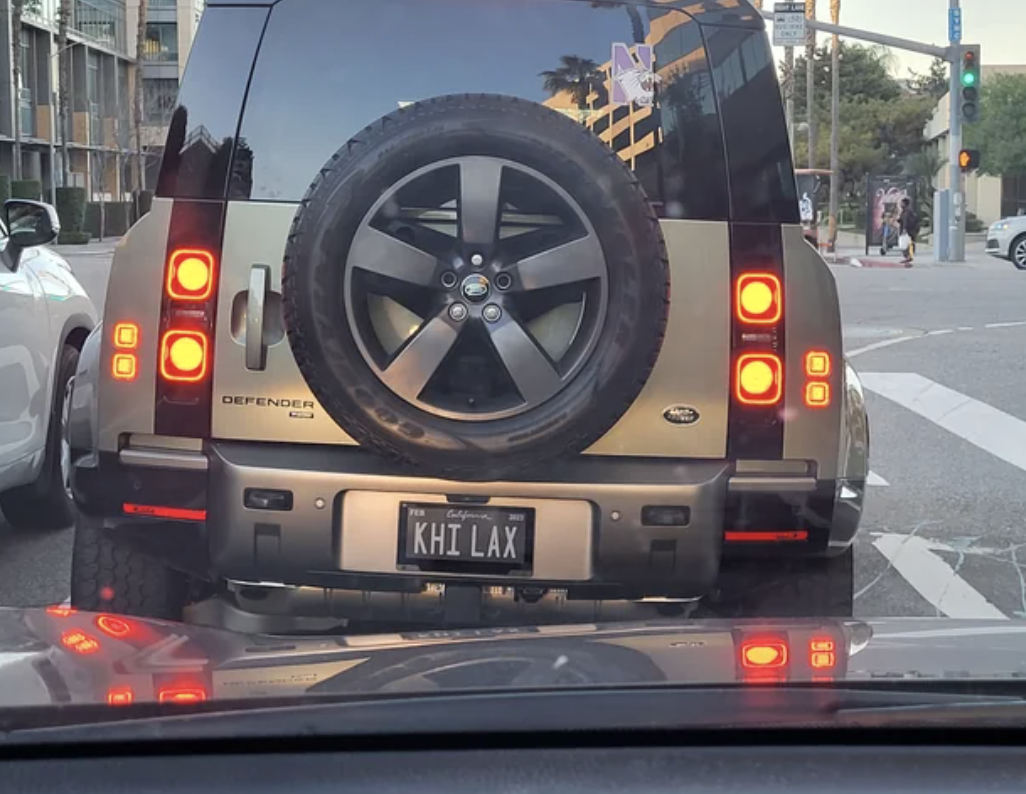 Rear view of a Land Rover Defender at a traffic stop with personalized plate &quot;KHI LAX&quot;