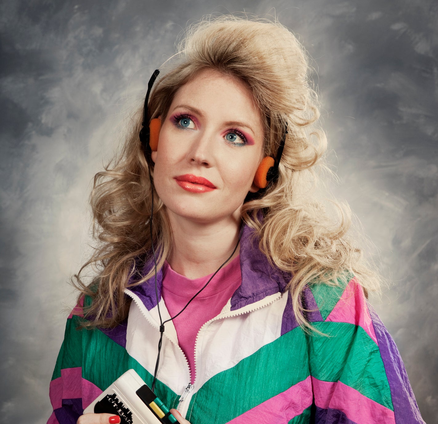 Woman in 1980s style attire holding a cassette player, with retro headphones
