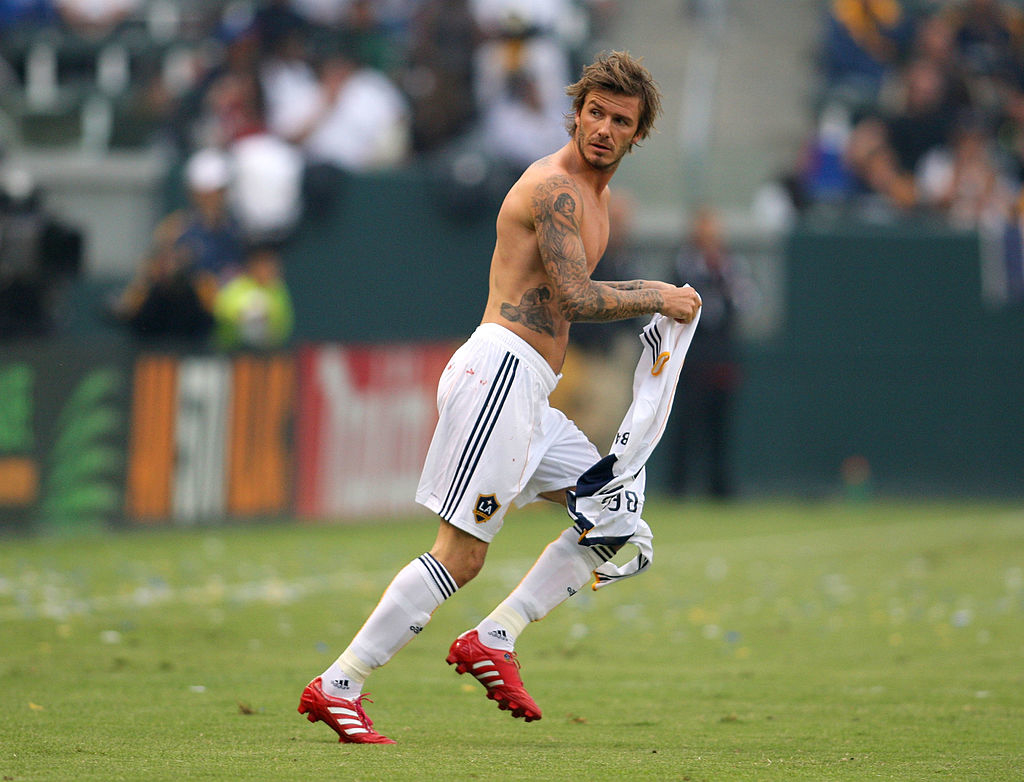 David Beckham in a soccer uniform, removing his jersey on the field