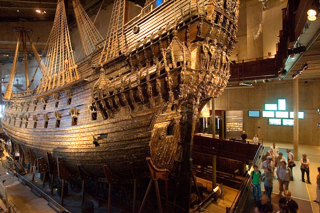 Preserved 17th-century warship on display with visitors observing in a museum setting