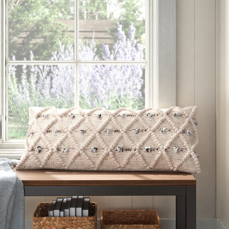 Decorative pillow with textured diamond pattern on a window seat