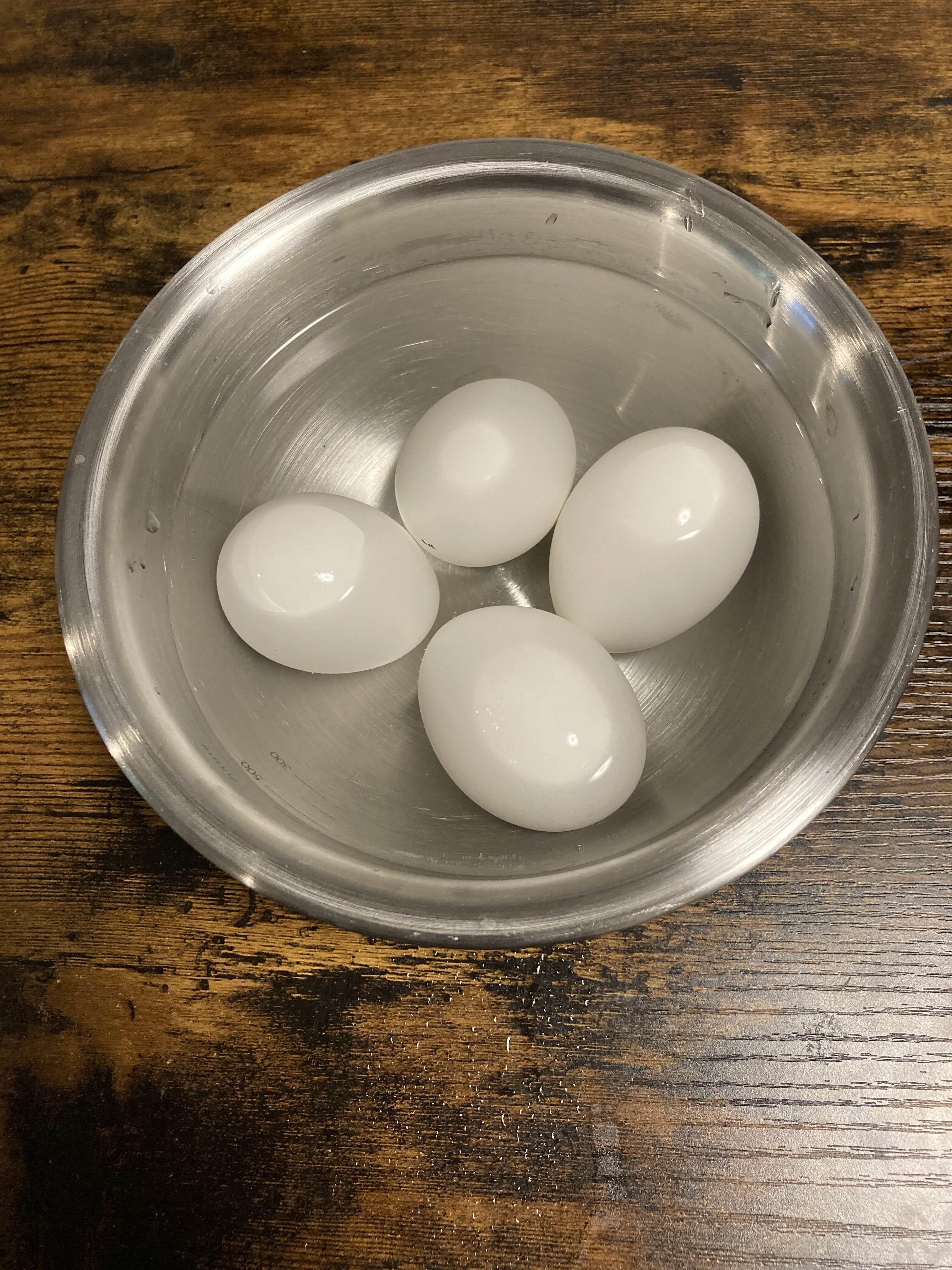 金属製のボウルに入った4つの白い卵。