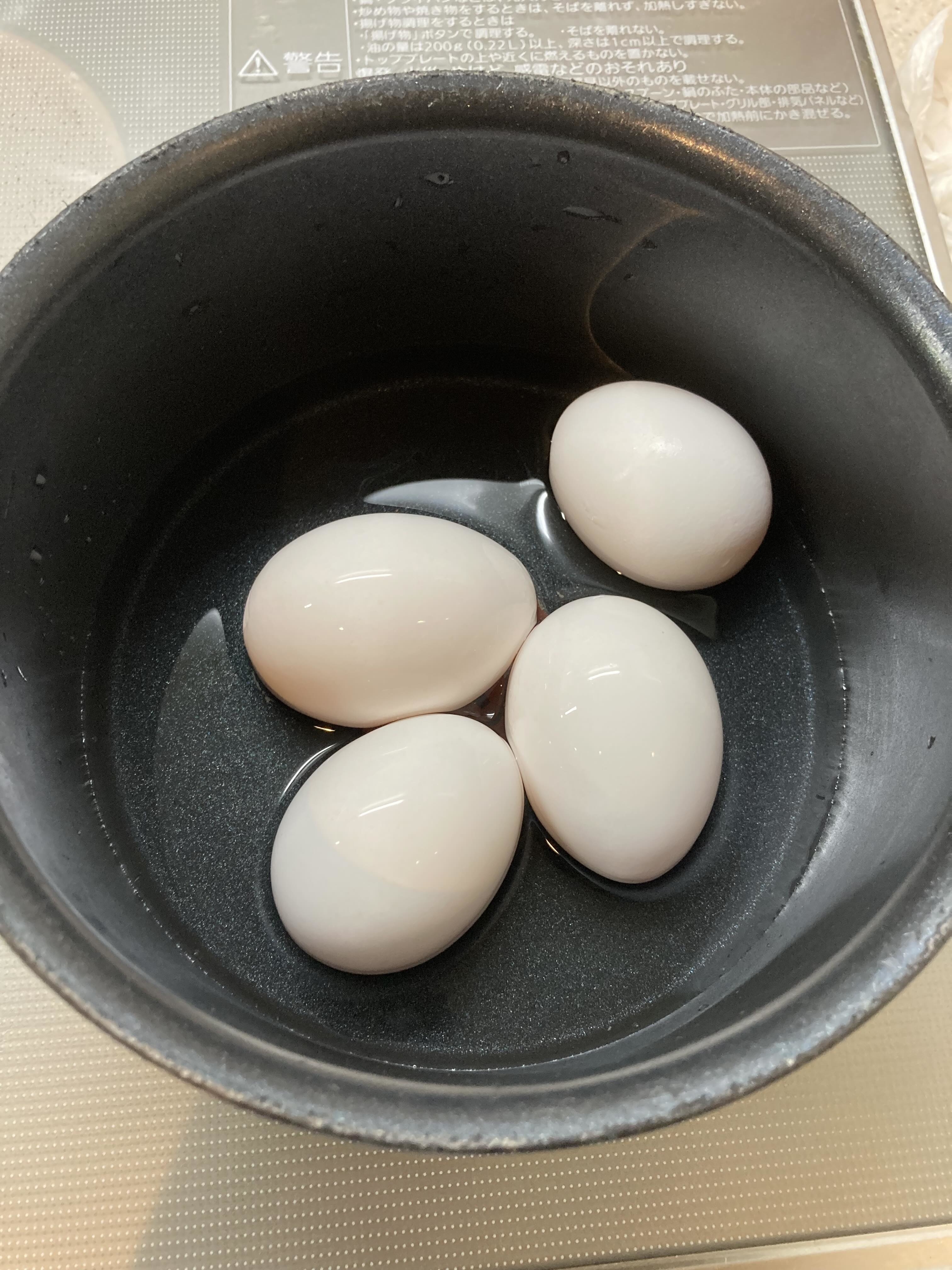 黒い鍋に入った四つの白い卵。