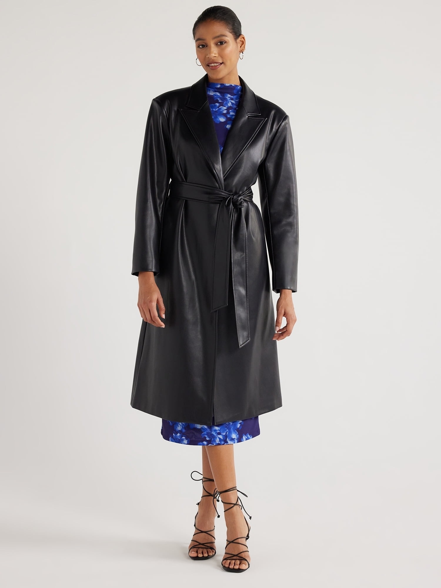 model in a black trench coat over a blue dress, paired with strappy sandals