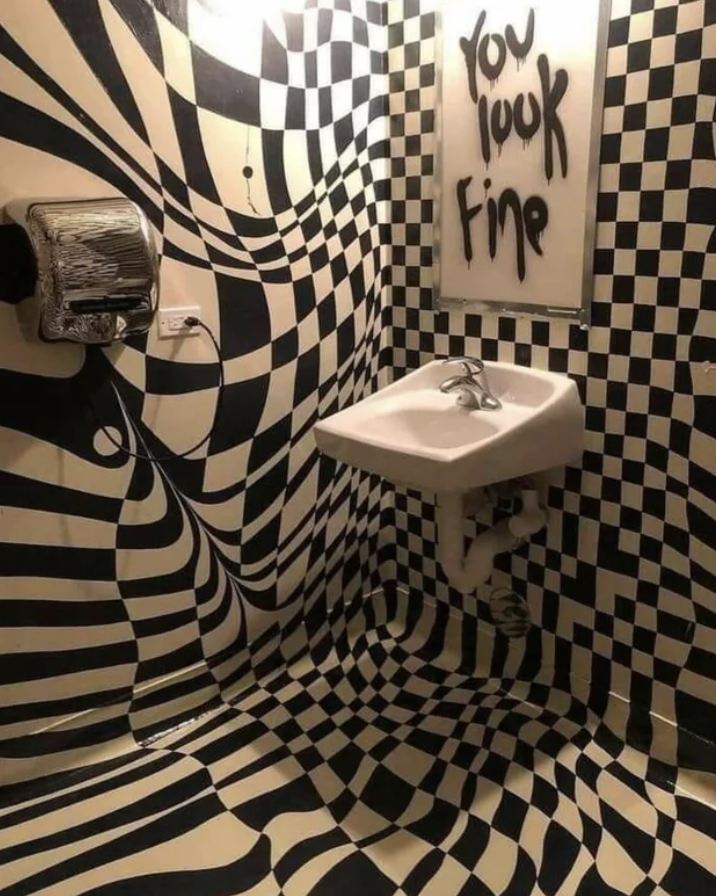 Optical illusion bathroom with checkered pattern and mirror message saying &quot;you look fine&quot;