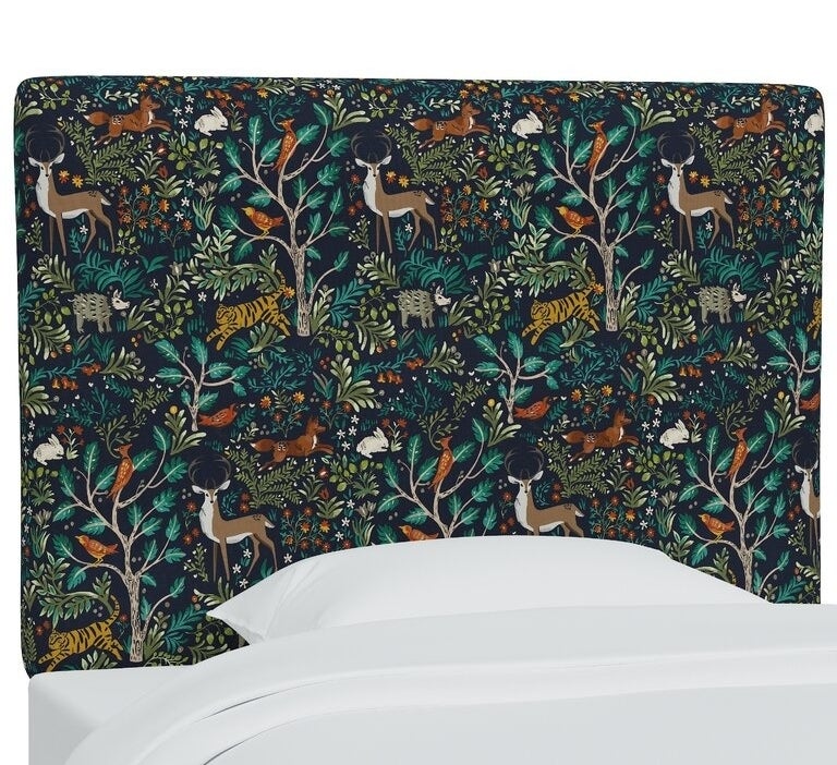 Patterned bed headboard with a forest and animal design in a bedroom setting