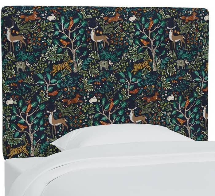 Patterned bed headboard with a forest and animal design in a bedroom setting