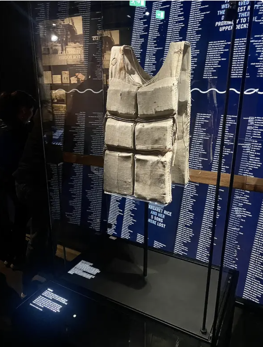 A life vest from the titanic is on display at an exhibition with informational text panels in the background