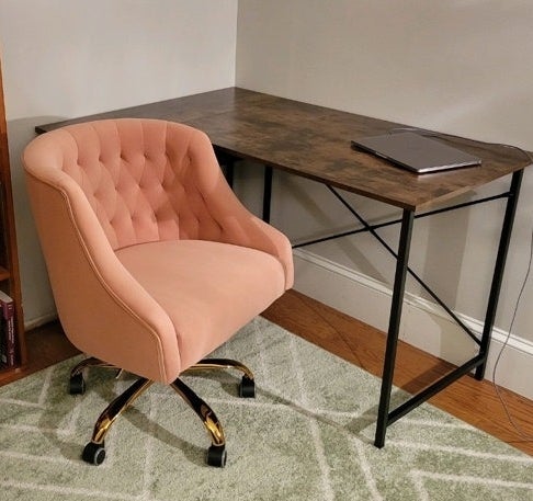 A pink tufted office chair with gold accents beside a desk
