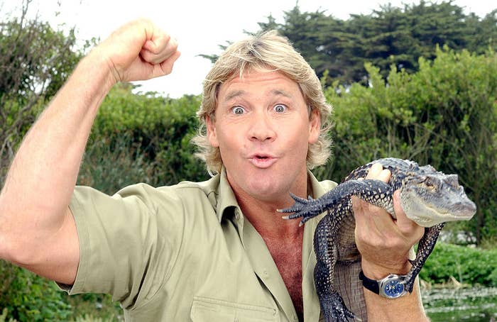 Man in khaki shirt posing excitedly with an alligator