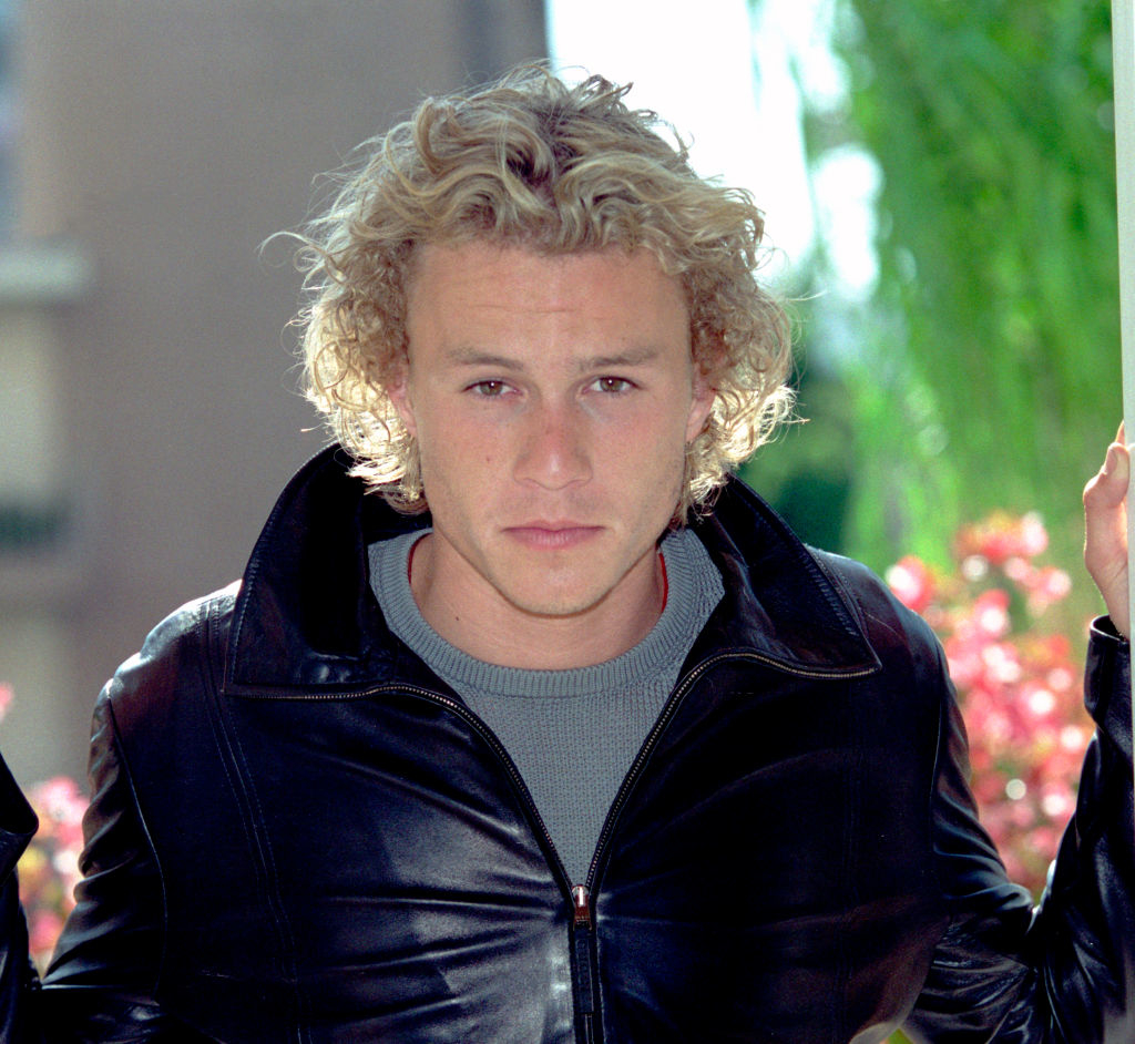 Man in leather jacket and wavy hair standing outside