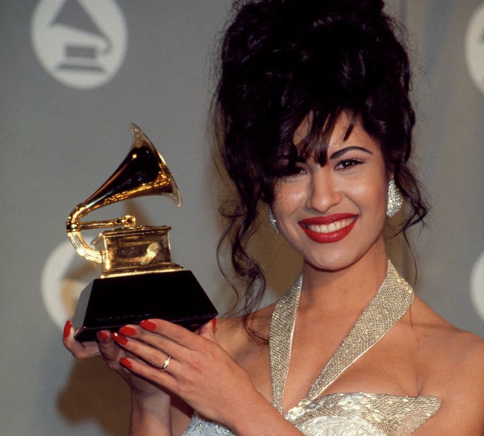 Woman holding a Grammy Award, wearing a sequined gown with spaghetti straps