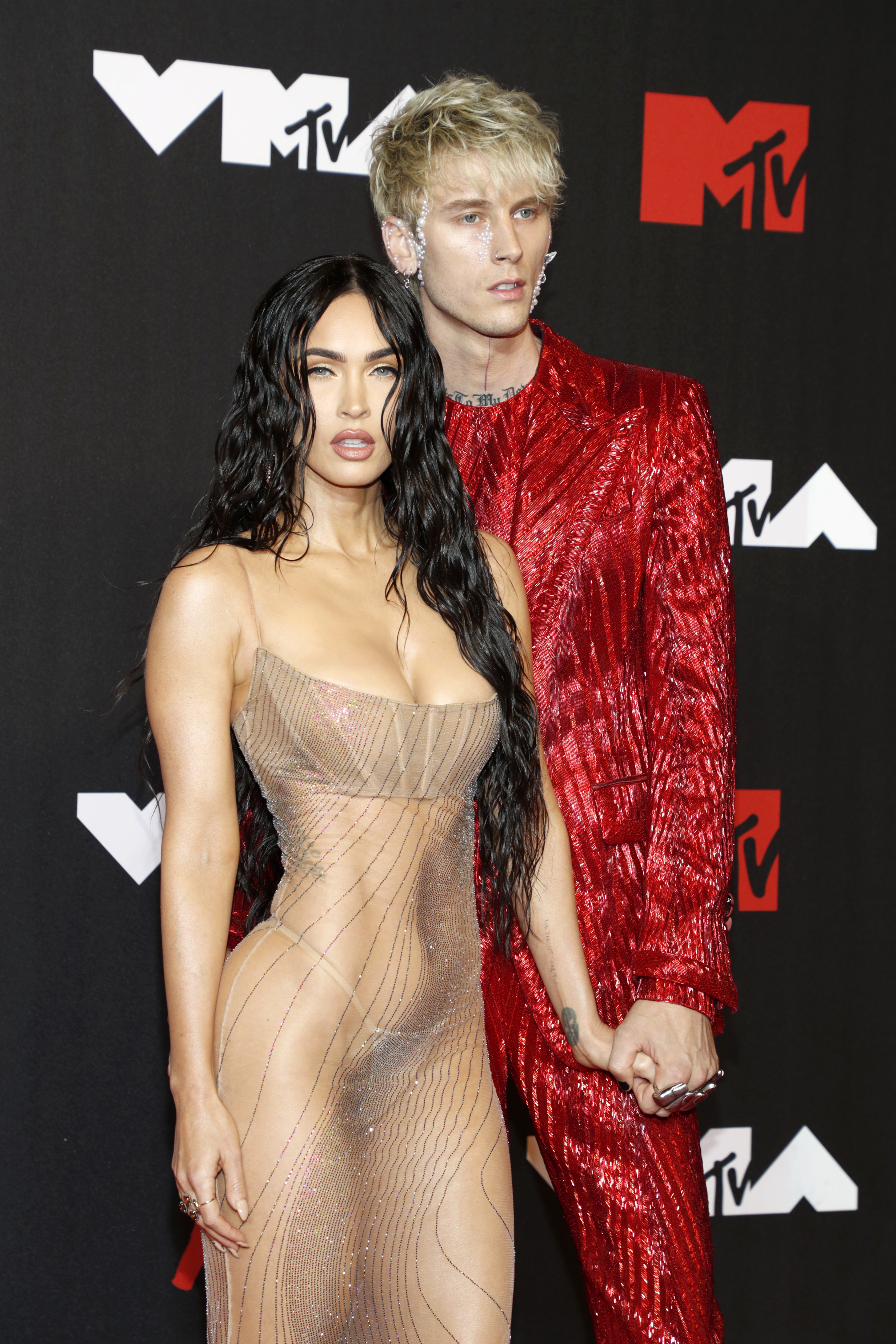 Megan in a sheer, beaded dress and MGK in a shiny red suit at the MTV VMAs