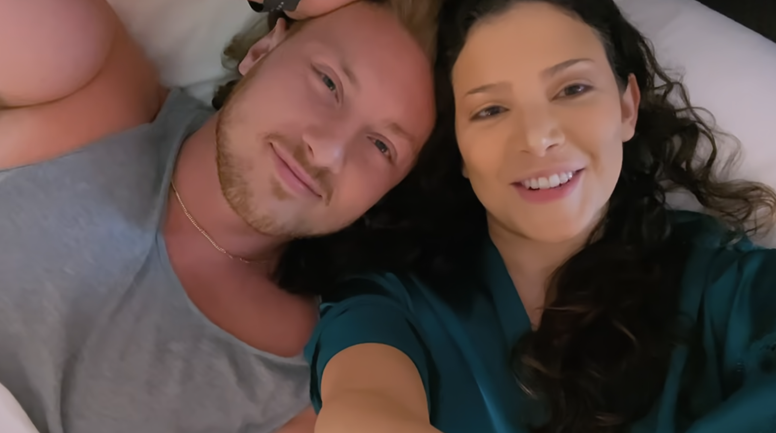 Amy and Johnny smiling while lying down, close-up selfie view