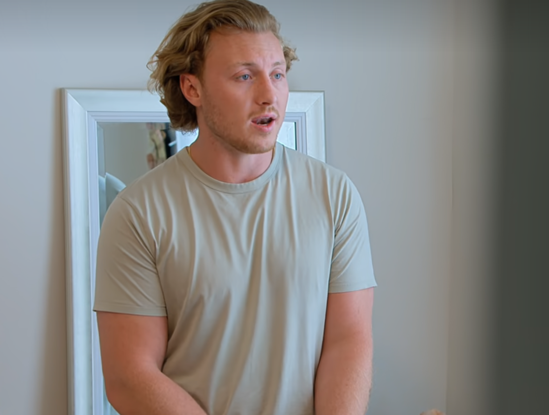 Man in a t-shirt speaking indoors, screen from "Love is Blind" featuring the progress bar of a video player
