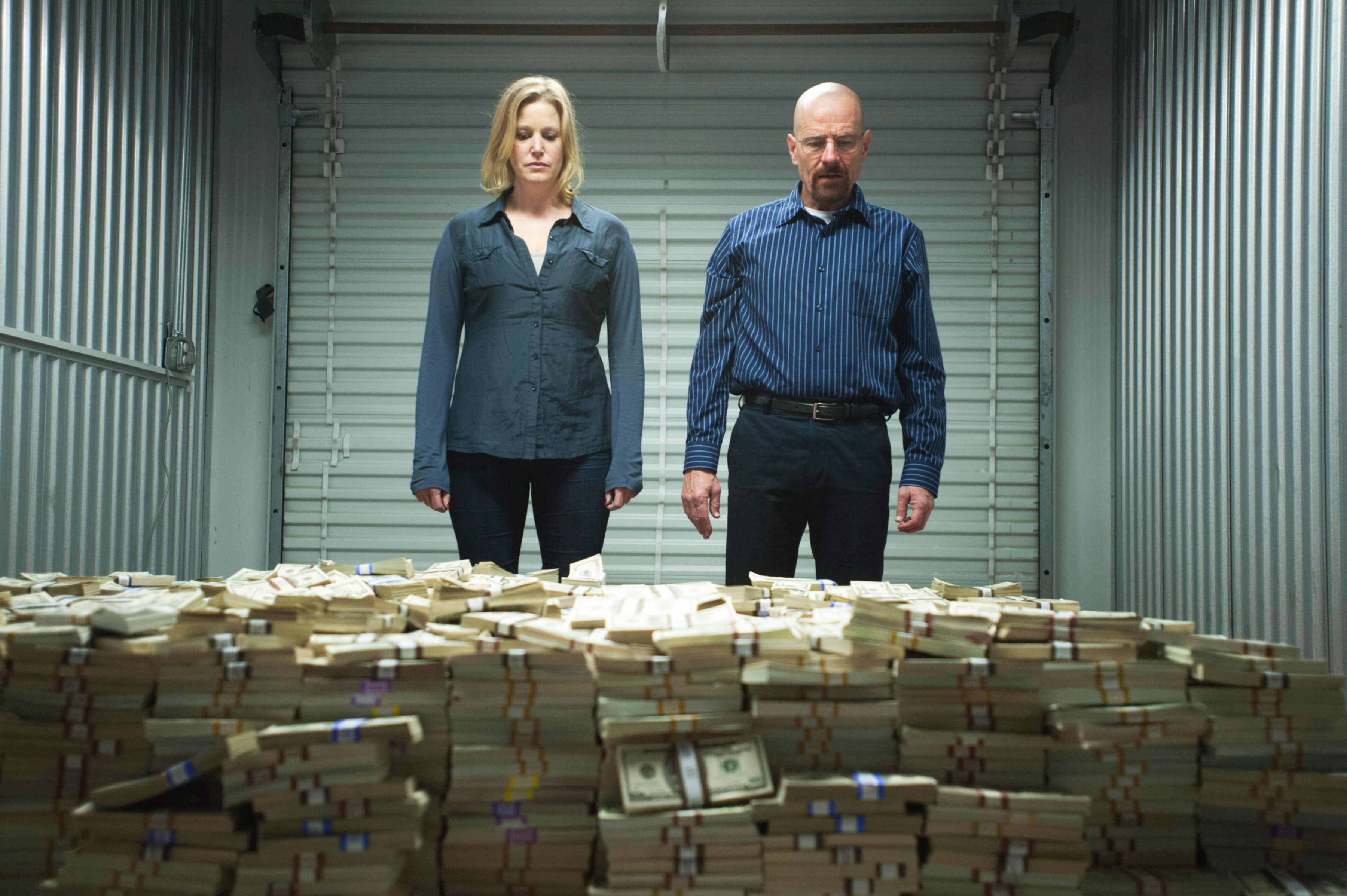 Skyler and Walter White standing with piles of money