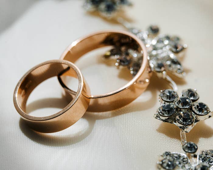 Two wedding rings with intricate jewelry on a textured fabric
