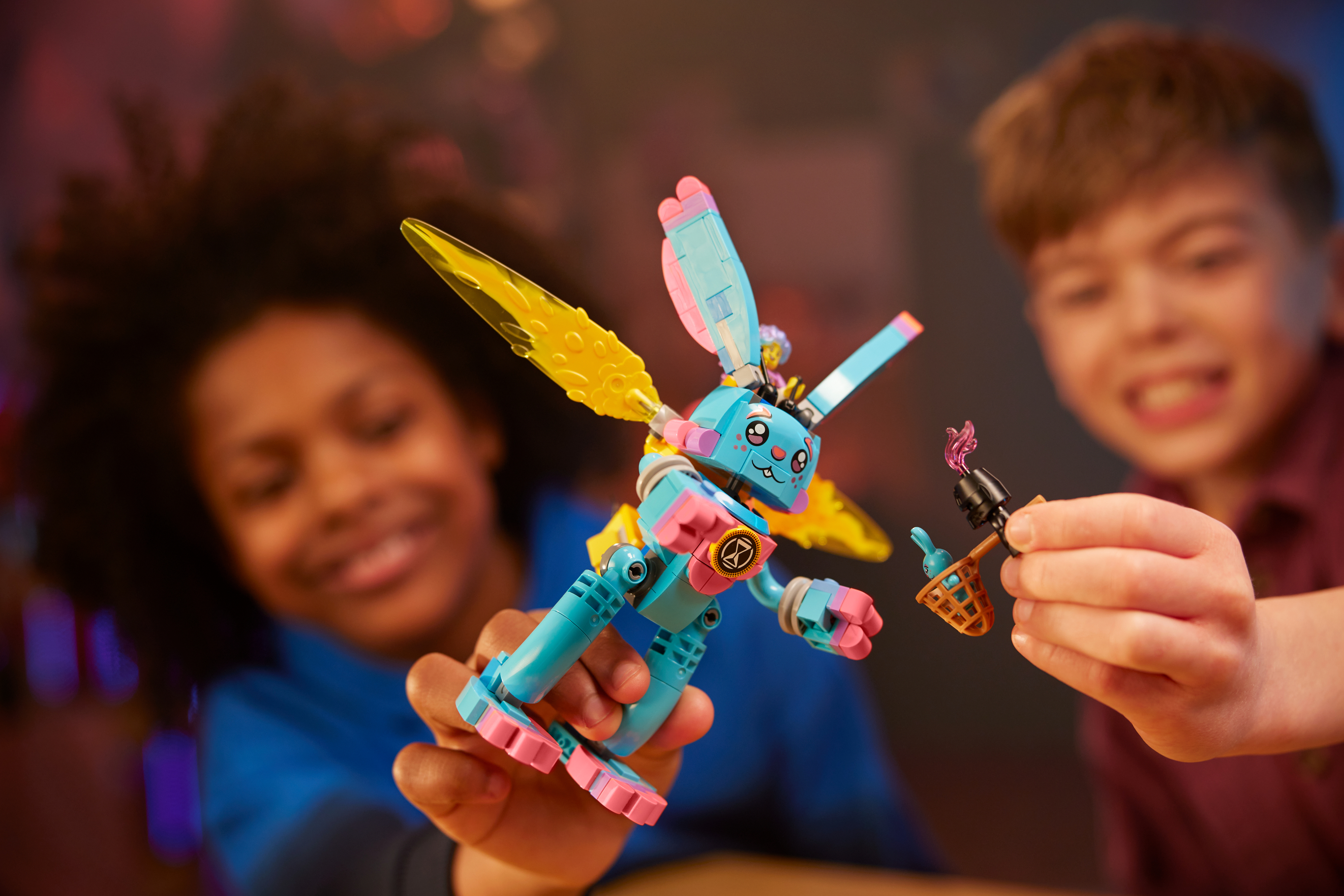 Two children smiling, one holding a colorful LEGO figure with wings