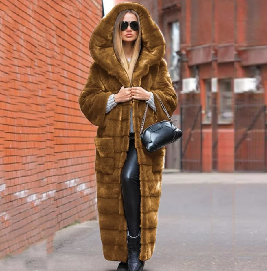 Woman in oversized fur coat with hood, carrying a black shoulder bag, walking in urban setting