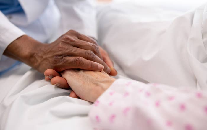 A healthcare worker&#x27;s hand gently holding a patient&#x27;s hand to provide comfort