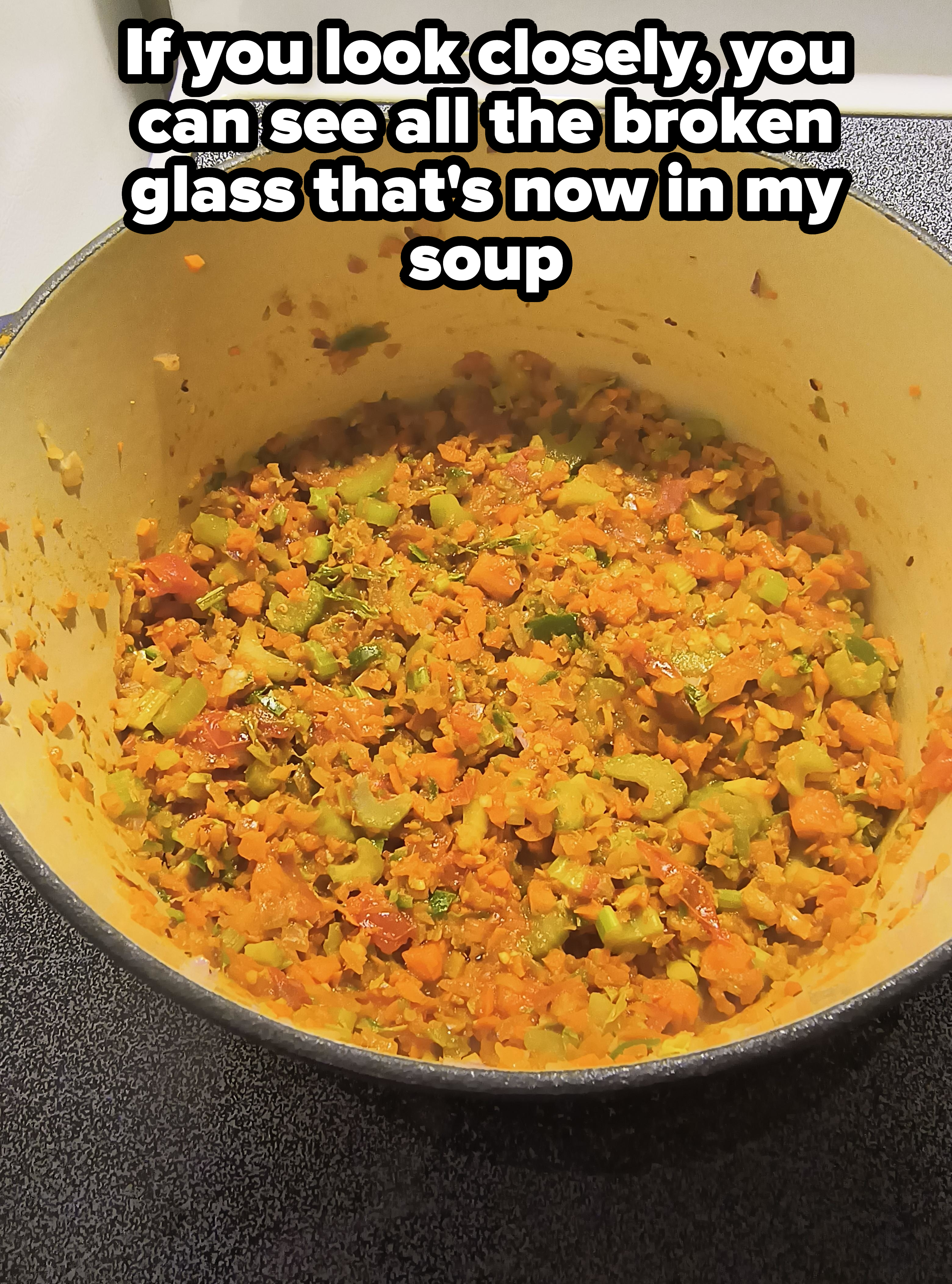 Pot with cooked mixed vegetables on a stovetop with small pieces of glass in it