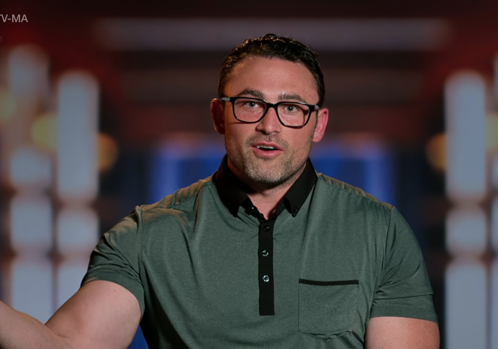 Matthew in glasses and a polo shirt gestures while speaking