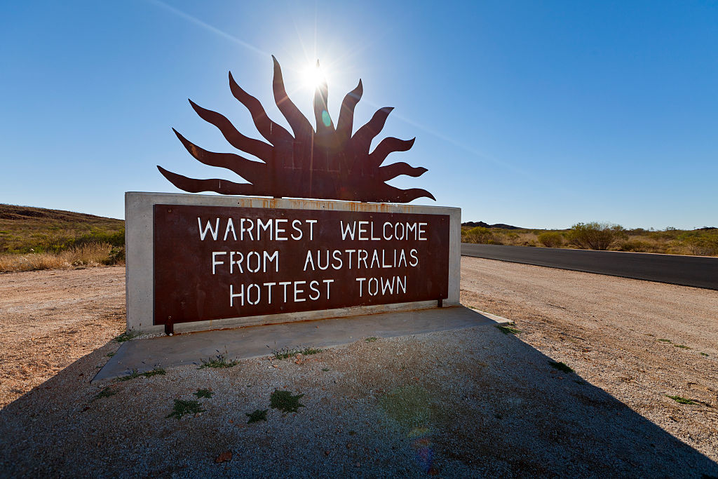 Sign reading &quot;Warmest welcome from Australia&#x27;s hottest town&quot; with a sun design, placed outdoors