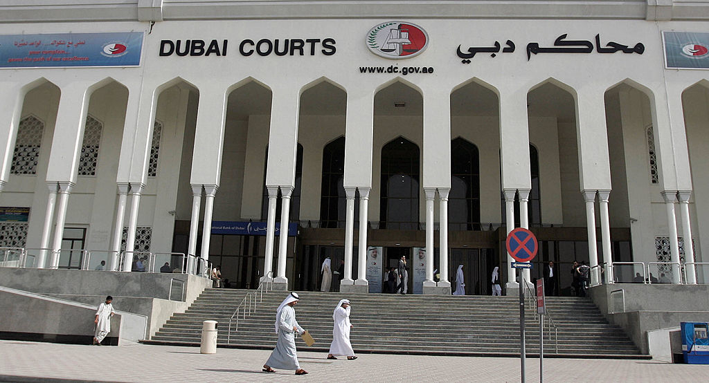 Dubai Courts building entrance with emblem and two people walking outside