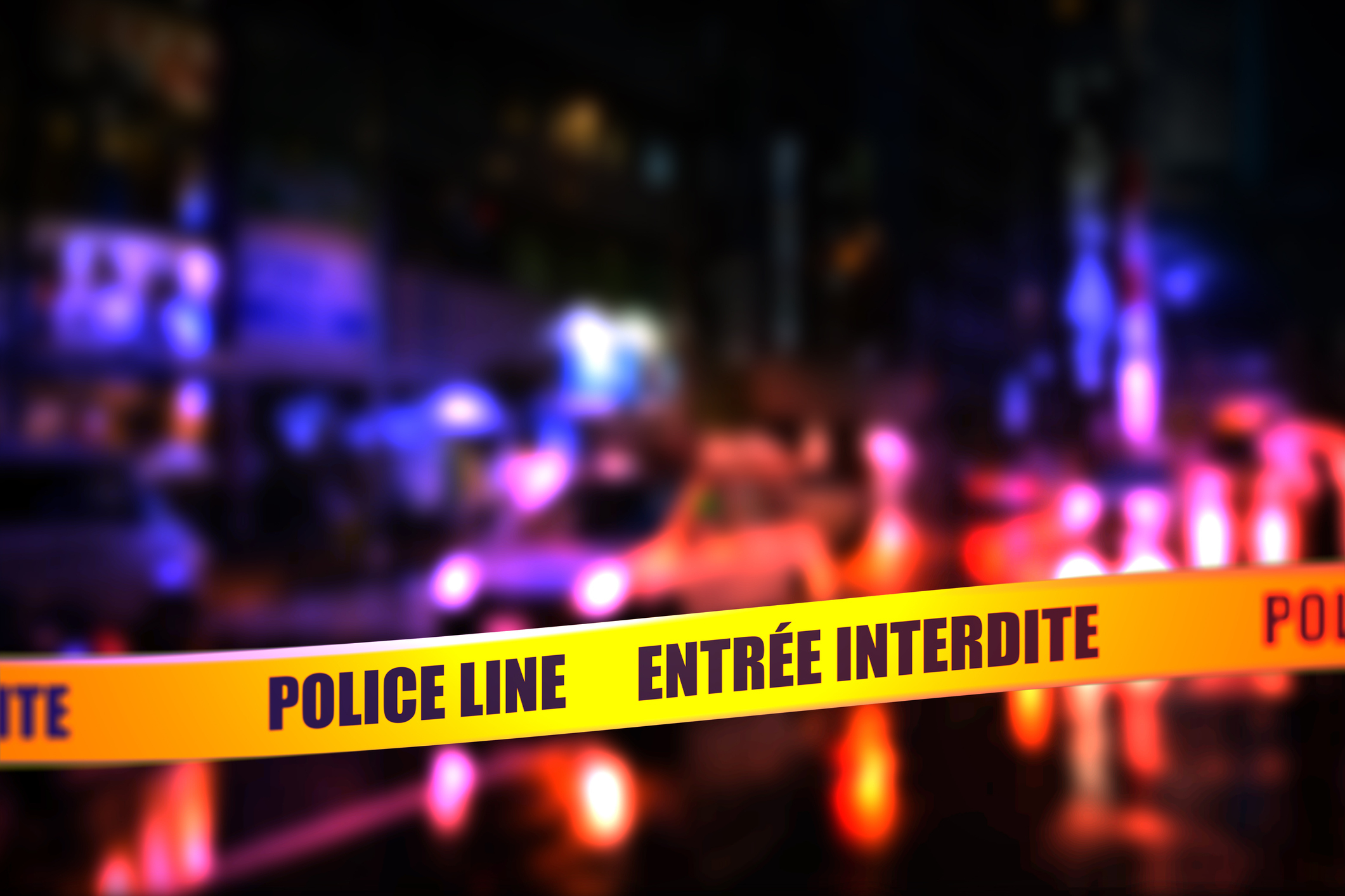Blurred nighttime scene with a focused &quot;POLICE LINE ENTRÉE INTERDITE&quot; tape across the foreground