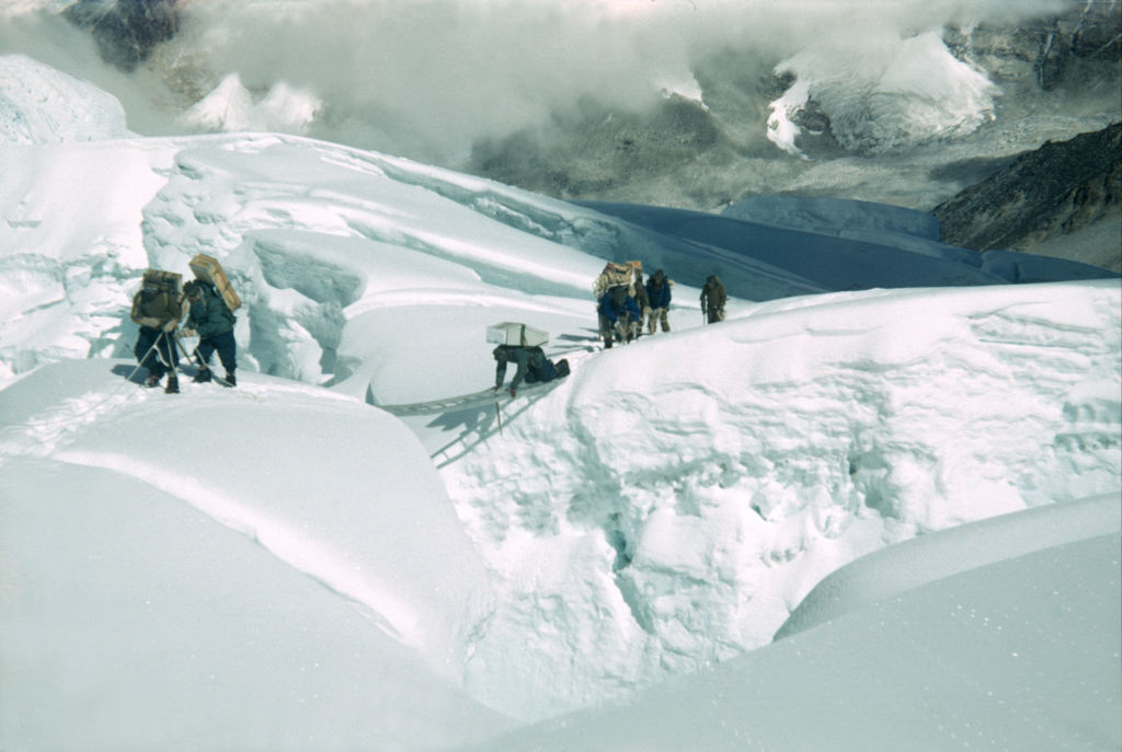 Group of hikers with backpacks traversing a snowy mountain ridge