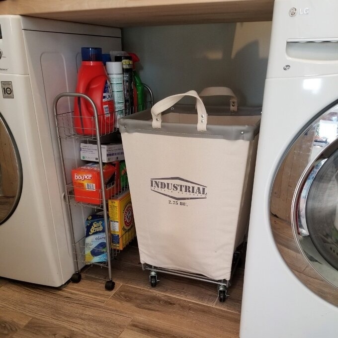 Laundry cart with &quot;INDUSTRIAL 2.5 BBL&quot; text next to a washer and dryer