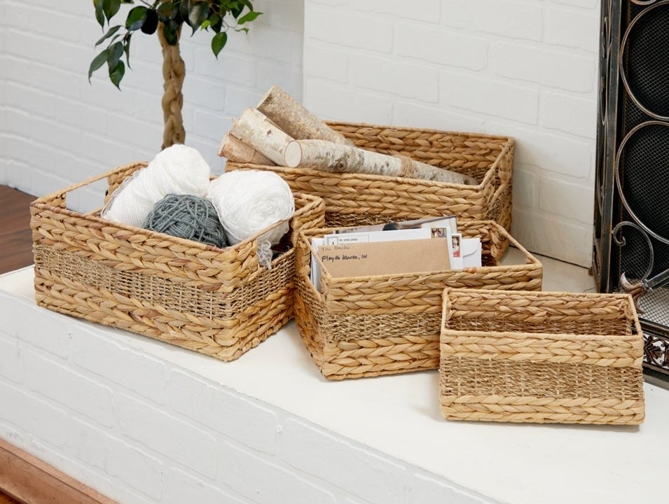 Three wicker storage baskets in ascending sizes with various items, such as yarn and envelopes, neatly arranged inside them
