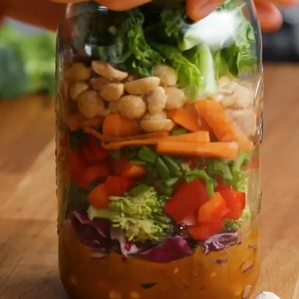 Layered salad in a jar with various vegetables and nuts, prepared for easy on-the-go eating