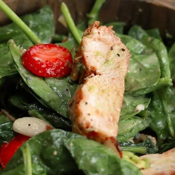 Grilled chicken slices on a bed of spinach salad with strawberries and beans