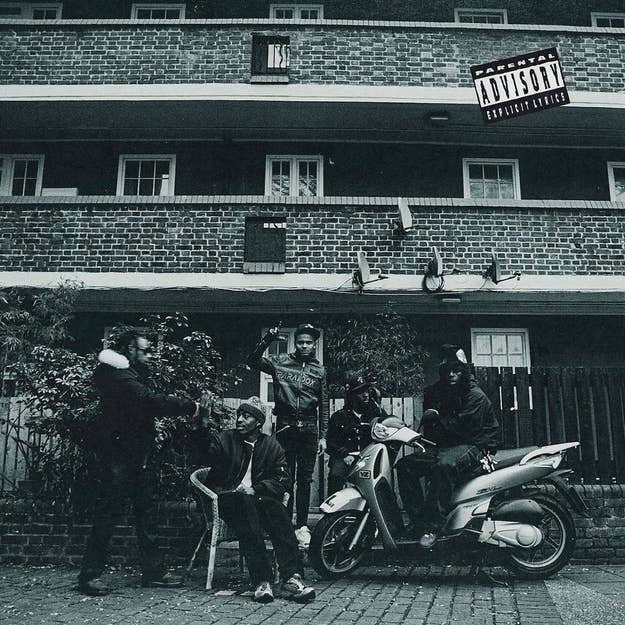 Group of people posing with a scooter in front of a building; includes a parental advisory label